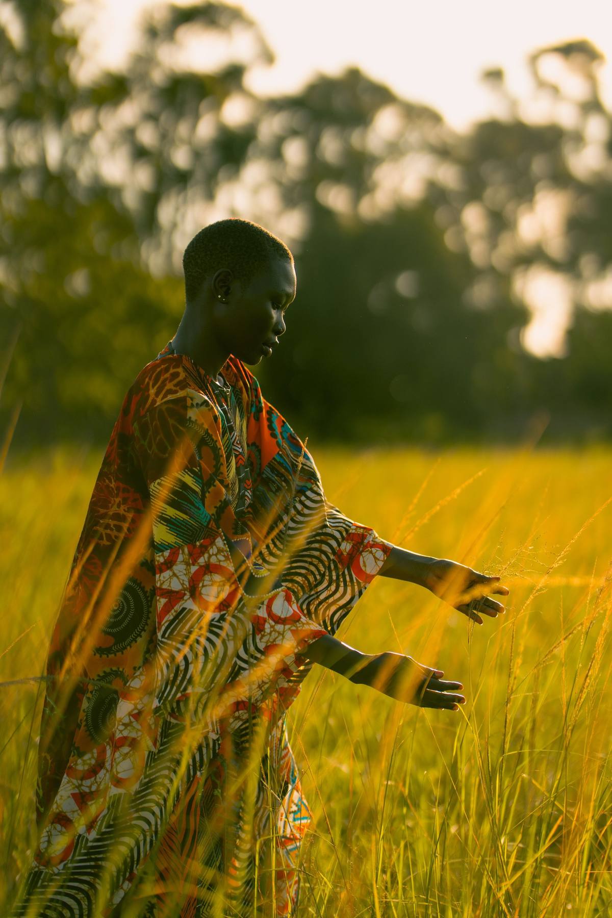 A woman in traditional print fabric walking through golden grassland light near South Luangwa