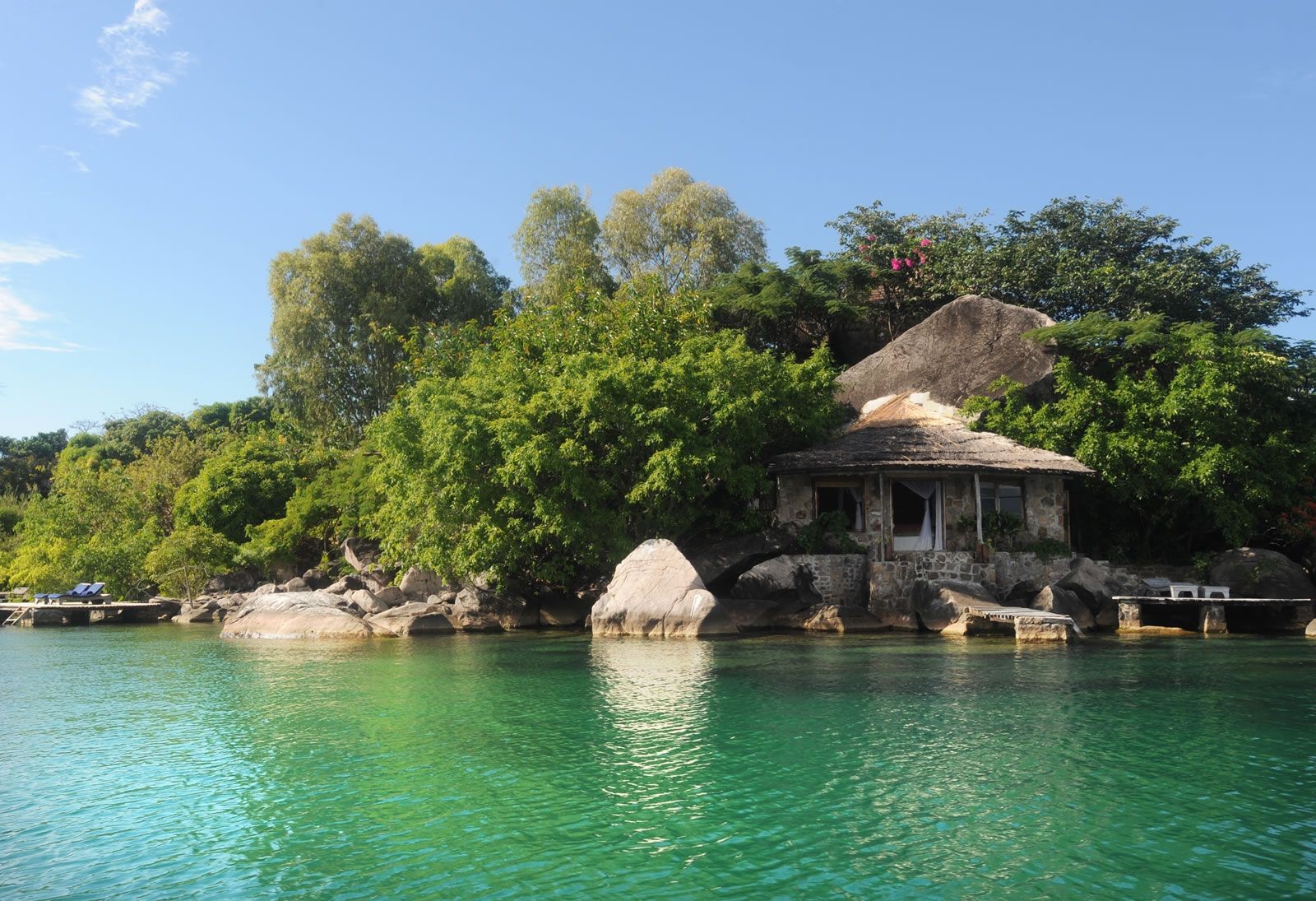 Traditional dugout canoes on a Lake Malawi beach framed by flowering bougainvillea