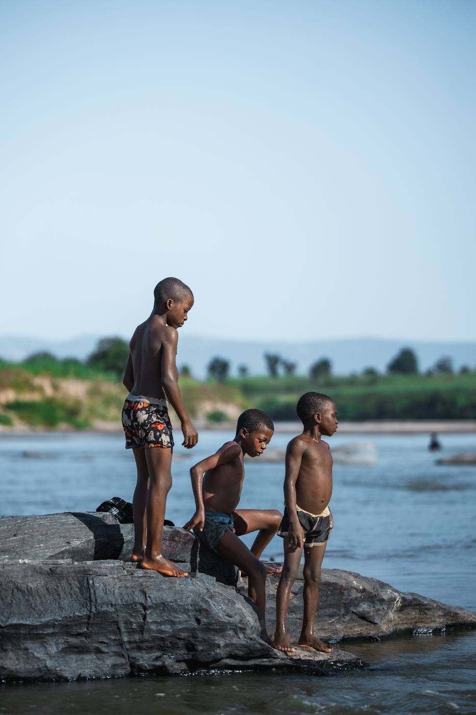 Local children playing on lakeside rocks, a scene from village life near Lake Malawi