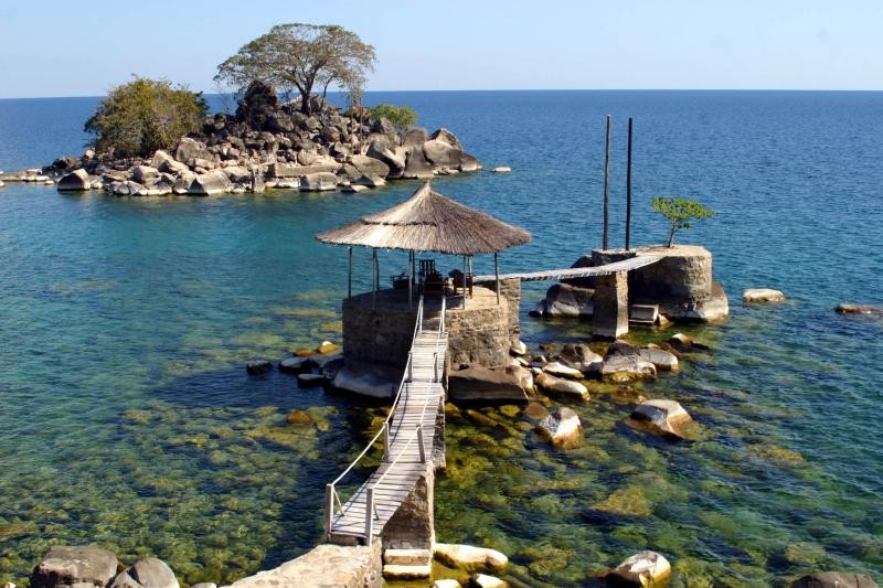 Aerial view of a thatched gazebo pier reaching out over Lake Malawi's clear shallows
