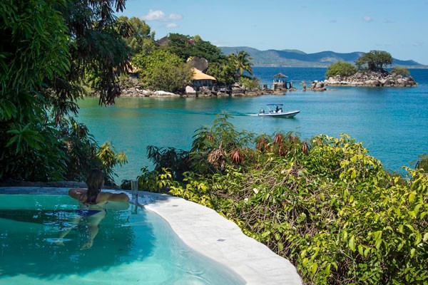 A guest relaxing in a private infinity pool overlooking Lake Malawi and a nearby island lodge