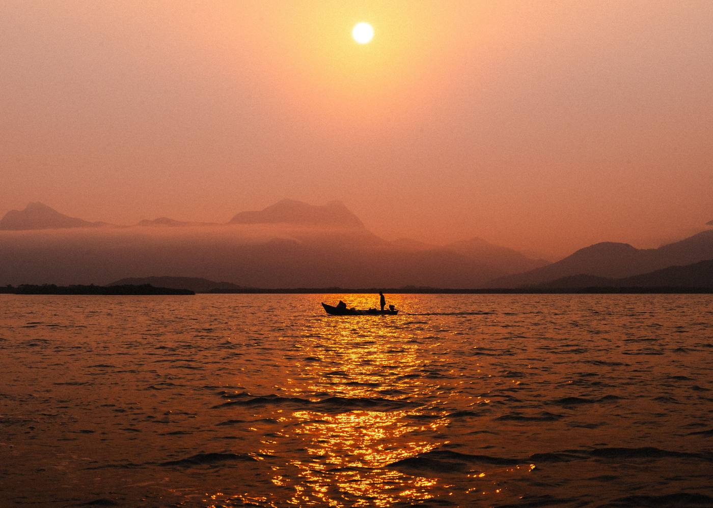 A hazy sunset over the mountains and water of Lake Malawi