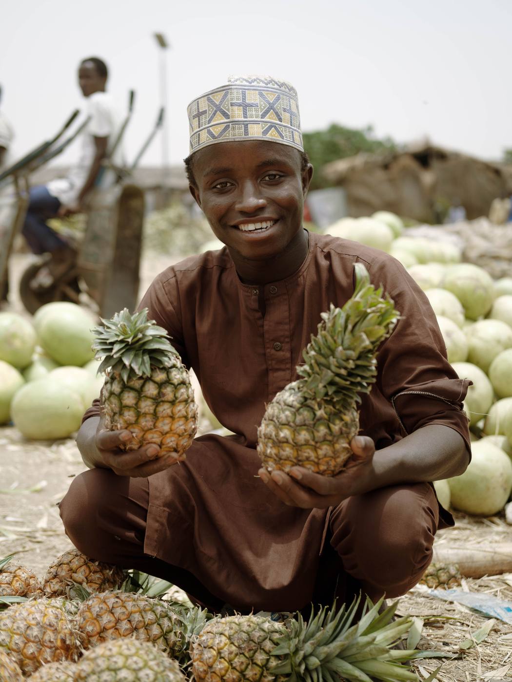 A young vendor with fresh pineapples at a Malawian market, part of a guided village culture tour