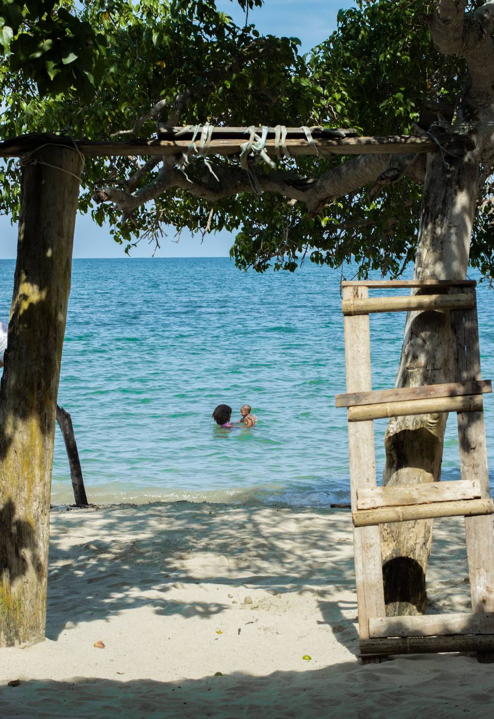 A mother and child swimming together in the calm, warm water of Lake Malawi