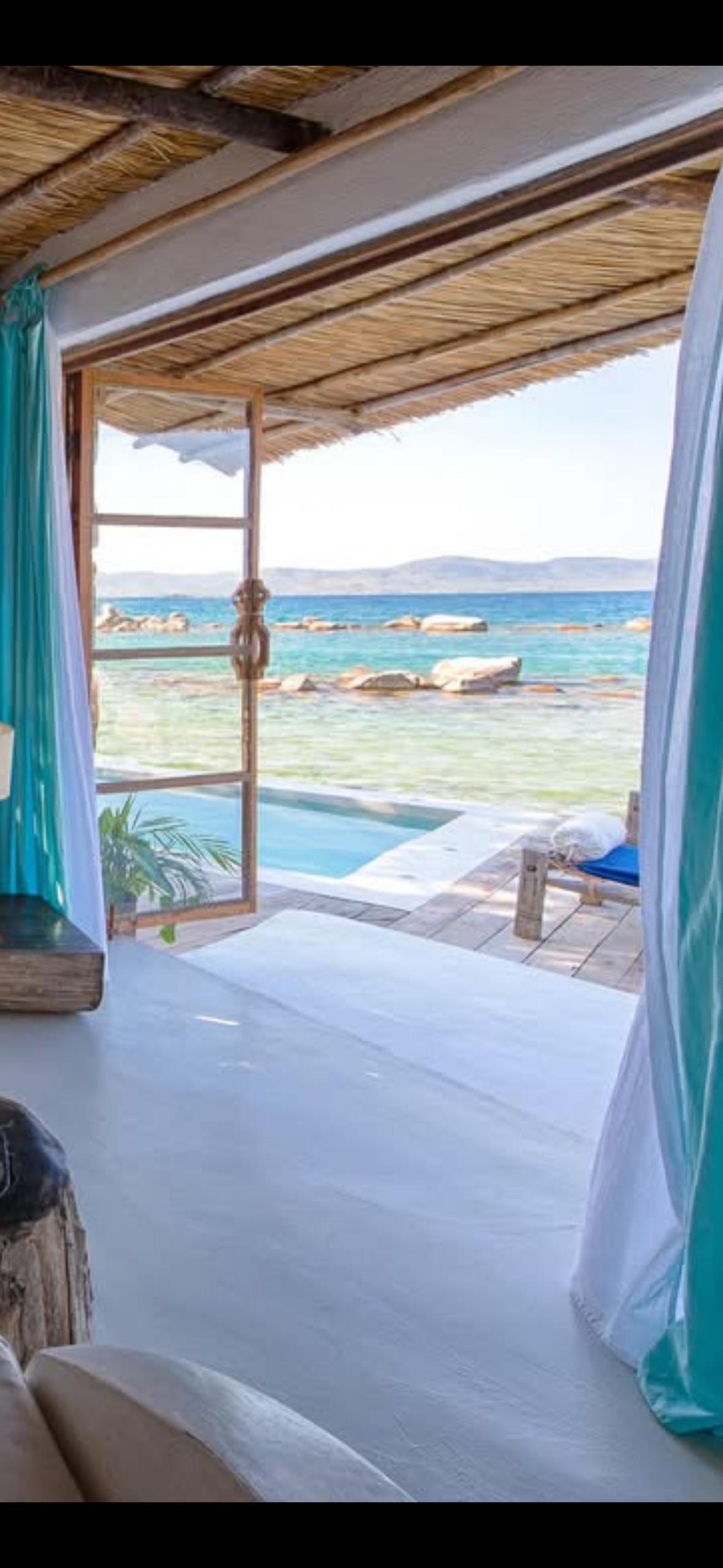 View from a private lakefront room through open doors to a plunge pool and Lake Malawi beyond