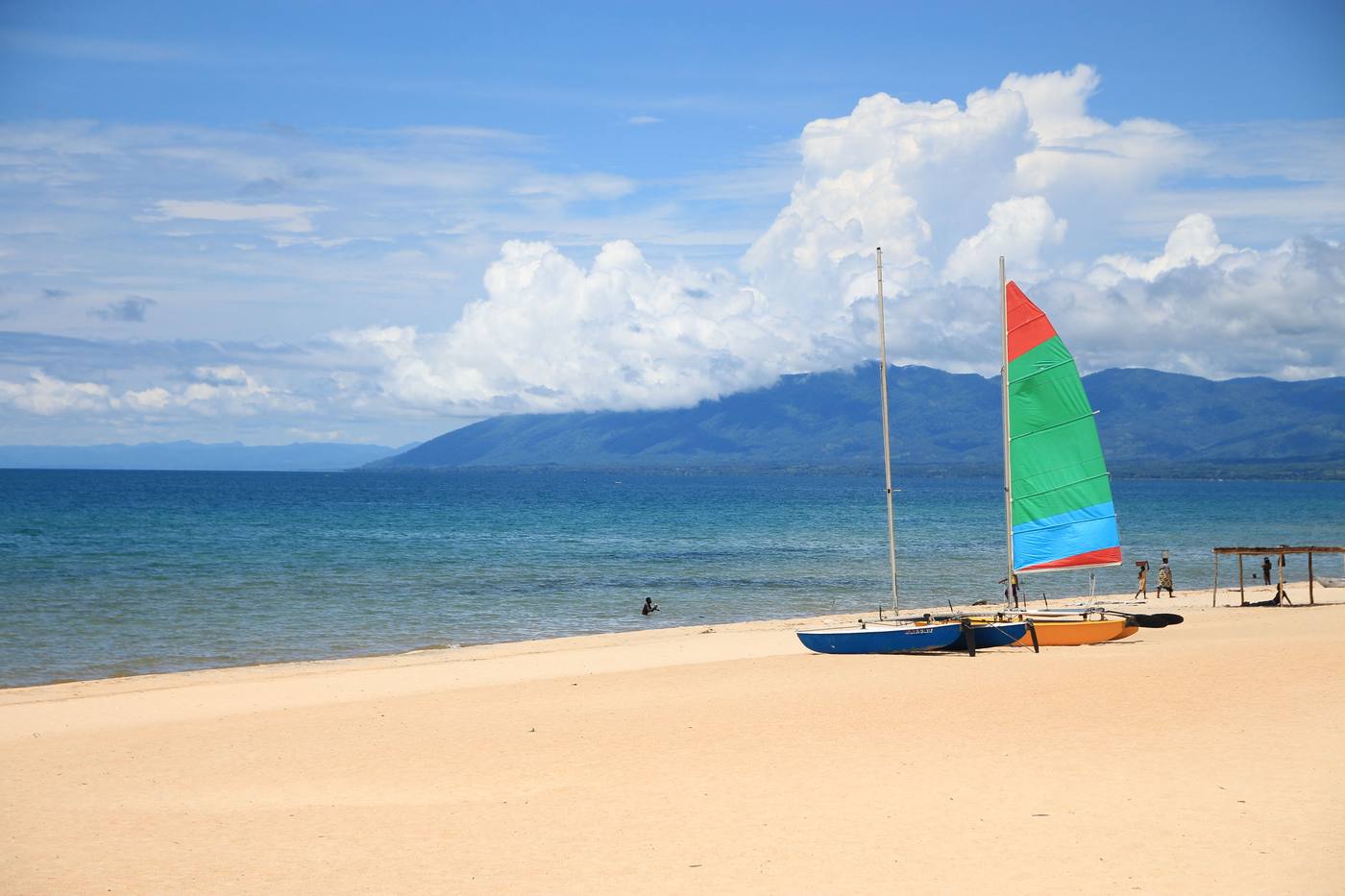 Colorful sailboats on a white sand beach on Lake Malawi, with mountains across the water