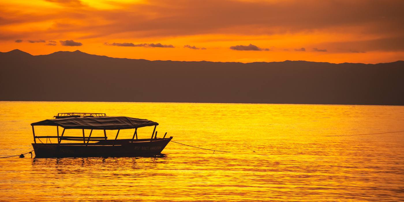 A covered boat at anchor on Lake Malawi at sunset